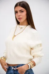 Sweater de punto con diseño de trenzas, color crudo, de cuello redondo y manga larga con puños acanalados.