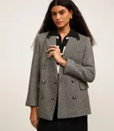 Blazer de tweed gris con diseño de espiga, doble botonadura, solapas de muesca, bolsillos cargo frontales y corte clásico.