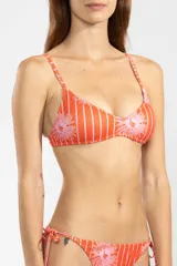 Bottom de bikini estilo triángulo, confeccionado en tejido reciclado con estampado pinstripe floral en tonos rojos y rosados. Presenta tiras ajustables a los laterales con terminaciones metálicas insignia de Polonio y forro interior para mayor comodidad.