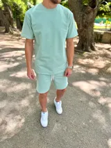 Conjunto deportivo para hombre compuesto por una remera de manga corta con cuello redondo y un short con cordón ajustable en la cintura, ambos en color verde menta.