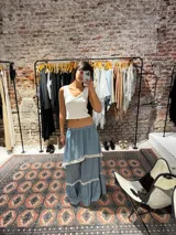 Pollera larga de algodón color celeste, con diseño de capas superpuestas y detalles de encaje blanco en los bordes de cada capa.