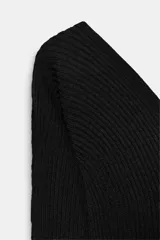 Top de punto acanalado color negro, con escote en pico tanto en el frente como en la espalda y mangas largas.