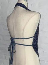 Top con escote halter y espalda descubierta, confeccionado en tela con lentejuelas azules.