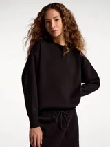 Buzo de cuello redondo con puños y ruedo elastizados, confeccionado en tejido de algodón. Presenta un diseño minimalista con un pequeño detalle bordado en la manga.