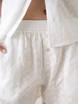 Short de broderie de algodón color blanco, con cintura elastizada, bolsillos laterales y botones decorativos frontales.