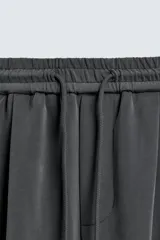 Pantalón jogger de corte wide fit confeccionado en tejido fluido con viscosa. Presenta un efecto lavado, cintura elástica ajustable con cordón, pliegues frontales, bolsillos laterales y un bolsillo trasero de plastrón.