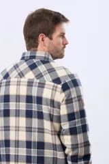 Campera leñadora de viyela a cuadros en tonos beige y azul oscuro, con interior forrado en corderito, cierre frontal con botones y dos bolsillos con solapa en el pecho.