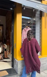 Ruana de lana Merino en color bordó, tejida en telar con diseño de hebras gruesas e irregulares y flecos en los extremos.