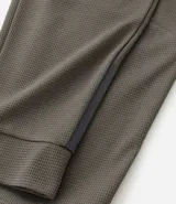 Pantalón deportivo de corte ajustado, confeccionado en tejido de poliéster texturizado color negro. Presenta cintura elástica con cordón de ajuste, bolsillos laterales con cierre y puños elásticos en los tobillos.
