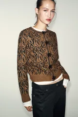 Chaqueta de punto con diseño jacquard de estampado animal en tonos marrón y negro. Presenta cuello redondo, manga larga y cierre frontal con botones decorados con abalorios.