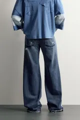 Jeans flare fit de denim azul oscuro con roturas y costuras decorativas en las perneras. Tiro medio y diseño de cinco bolsillos.