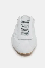 Zapato deportivo destalonado de tejido gris claro, con cordones y suela engomada con relieve de color caramelo.