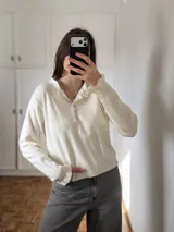 Sweater de tejido bremer color blanco, con cuello polo y cierre frontal de botones, de manga larga y ajuste clásico.