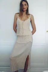 Falda midi de tiro bajo confeccionada en mezcla de viscosa con tejido efecto arrugado. Presenta una cintura con tejido en superposición combinado a tono y una abertura lateral en el bajo.