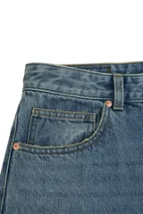 Jean de corte baggy con silueta holgada y relajada, confeccionado en denim de algodón con lavado azul clásico. Presenta diseño de cinco bolsillos, cintura con trabillas y cierre frontal con botón y cremallera.