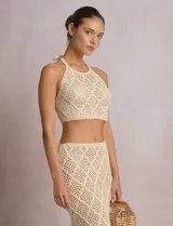 Top crop de tejido calado beige, con escote halter y patrón geométrico de rombos.