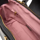 Cartera de mano y hombro color negro, estilo tote bag pequeño, con doble asa corta y correa larga desmontable y regulable. Presenta un bolsillo frontal con solapa y broche dorado, y herrajes metálicos dorados.