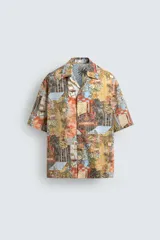 Camisa de corte relajado confeccionada en tejido ligero de algodón, con cuello bowling y manga corta. Presenta un estampado integral con motivos urbanos y tropicales en tonos cálidos.