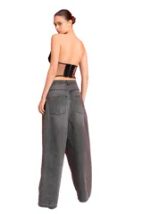Jean de tiro bajo con corte extra oversize y pierna ancha, confeccionado en denim gris con efecto lavado localizado en la zona de la cadera.