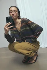 Cardigan de punto marrón con escote en V y cierre frontal con tiras para atar. Presenta diseño de rayas horizontales con patrón en zigzag de colores vibrantes como naranja, verde lima, azul y rosado.
