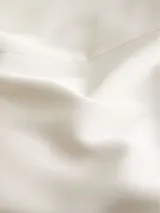 Blusa blanca de satén con cuello redondo con abertura en forma de V y mangas cortas.