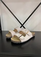 Sandalias planas color crudo, con dos tiras anchas ajustables con hebilla y costuras a contratono.