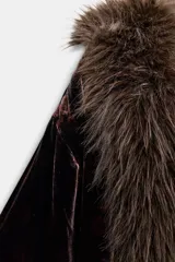 Abrigo largo de terciopelo en tono marrón oscuro, con cuello solapa y puños adornados con aplicación de pelo sintético. Presenta un diseño abierto con forro interior en color rojo con estampado floral.