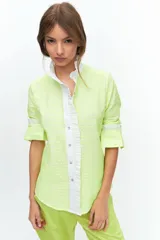 Camisa de manga larga confeccionada en broderie de algodón con bordados en hilo flúo color naranja. Presenta cuello mao, cartera frontal con volados y puños con volados.