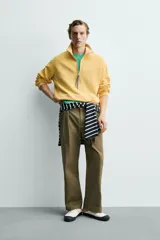 Sudadera de corte relajado confeccionada en algodón con interior de rizo, color amarillo mostaza con efecto lavado. Presenta cuello subido con cierre frontal de cremallera y detalle de cinta trenzada en el tirador, manga larga y acabados en rib.