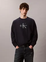 Buzo de felpa azul marino con cuello redondo, manga larga y el logo de Calvin Klein estampado en el pecho. Presenta puños, cuello y dobladillo acanalados.