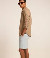 Bermuda masculina slim confeccionada en sarga de algodón con elastano, con bolsillos laterales, bolsillos traseros con botón, trabillas en la cintura y cierre frontal de botón y cremallera.