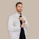 Campera bomber blanca de nylon con cierre frontal, cuello alto y puños y ruedo acanalados con detalles en gris, rojo y negro.