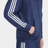 Campera con capucha Adidas Adicolor de corte holgado, color azul con cierre frontal de cremallera. Presenta las icónicas tres rayas blancas en las mangas y el logo del trébol bordado en el pecho.