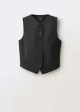 Chaleco de sastre color negro, con cuello en pico y cierre frontal de botones. Presenta un diseño recto, sin mangas y cuenta con dos bolsillos de ribete en la parte delantera.