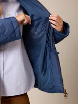 Campera acolchada de diseño matelassé con patrón de rombos, color bordó. Presenta cuello camisero, cierre frontal con cremallera metálica, cintura entallada con elástico y bolsillos laterales. Incluye un pequeño bordado distintivo en el pecho.