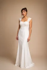 Vestido largo de novia color blanco marfil, con cuerpo de tul bordado con perlas y apliques florales, escote cuadrado y falda fluida de corte sirena.