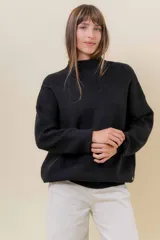 Sweater tejido de punto color blanco, con cuello alto y diseño en relieve tipo chevron en la parte frontal. Presenta un calce holgado con terminaciones acanaladas en puños y ruedo.