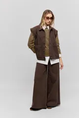 Chaleco de jean negro, de calce relajado con hombros caídos, cuello camisero, cierre frontal con botones y grandes bolsillos aplicados.