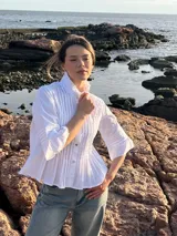 Camisa blanca de poplin de algodón con alforzas verticales y cuello alto estructurado. Mangas 3/4 con detalle de pliegues.