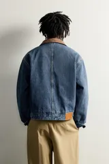 Cazadora relaxed fit de denim de algodón con interior ligeramente acolchado, cuello de pana marrón a contraste, bolsillos de plastrón en el pecho y cierre frontal con botones. Incluye un parche con gráficos Fruit of the Loom en el pecho.
