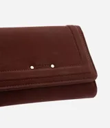 Billetera mediana Satinato tipo sobre, confeccionada en suede marrón con solapa frontal, detalles de costuras pespunteadas, apliques metálicos y cierre de botón a presión.