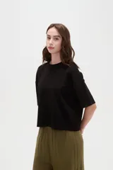 Remera blanca de manga corta, con cuello redondo a la base y diseño holgado.