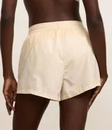 Short deportivo femenino tipo runner de la marca Get Over, color beige, confeccionado en poliamida con cintura elástica, cordón de ajuste y recortes con hilo reflectante.