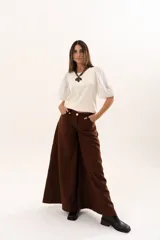 Pantalón de tiro medio con corte súper campana, confeccionado en tela de textura suave. Presenta cierre frontal con cremallera y botón, bolsillos delanteros y traseros, y costuras verticales que definen su estructura.