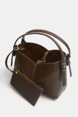 Bolso mini shopper de diseño trenzado en color beige, con asas de mano y correa bandolera extraíble en tono marrón. Presenta detalle de pespuntes en contraste y cierre interior con cremallera.