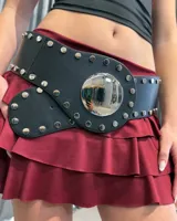 Cinturón ancho de cuero sintético negro con diseño de tachas metálicas plateadas y una gran hebilla circular central con acabado espejado.