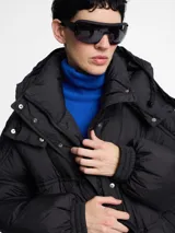 Campera puffer larga color blanco hueso, de corte amplio, con cierre frontal y capucha.