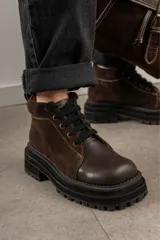 Borcegos de punta cuadrada con diseño acordonado, combinando paneles de cuero texturizado y gamuza en tonos marrones. Presentan una suela track gruesa de goma negra y cordones negros.
