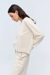 Sweater de tejido de punto color beige, con escote en V y calce holgado.