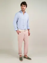 Camisa celeste a rayas verticales de lino, corte regular fit, cuello italiano, cierre con botones, manga larga terminada en puño simple y logo bordado en el pecho.